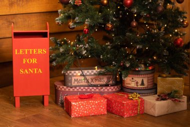 Noel ağacının yanındaki ambalaj kağıdına sarılı Noel hediyeleriyle dolu kutular. Noel tatili atmosferi