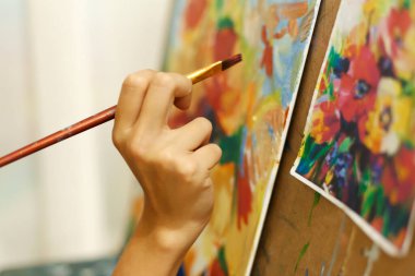 Yakından ressam yağlı boyalarla tuvale bir resim çiziyor..