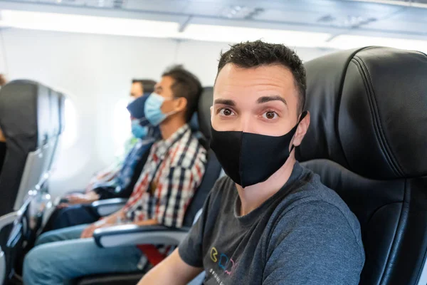 Uçak yolcuları yüzlerine tıbbi maske takıyorlar. Koronavirüs salgını sırasında hava yolculuğu. Havayolu gereksinimleri