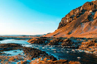 İzlanda 'nın kışın nefes kesici dağ manzarası, şelaleli bir nehir. Doğa boyaları.