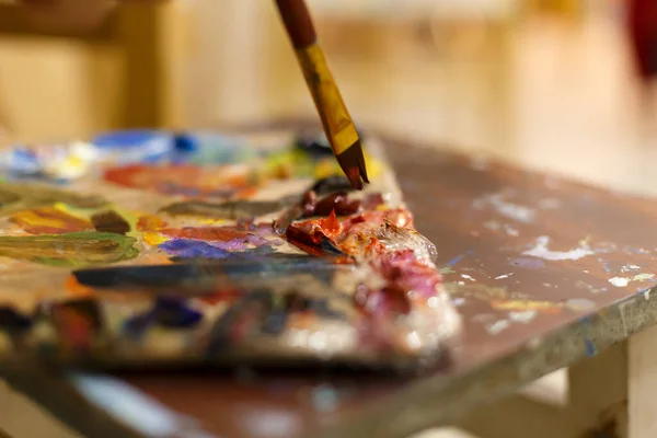 Close-up of an easel with paints, the artist paints a brush. Painting a picture