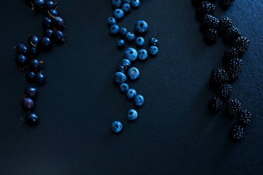 Siyah bir masada farklı türde böğürtlenlerin karışımı. Şık mevsimlik vitaminler.