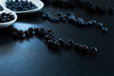 Siyah bir masada beyaz bir tabakta farklı türde siyah böğürtlen. Şık mevsimlik vitaminler.