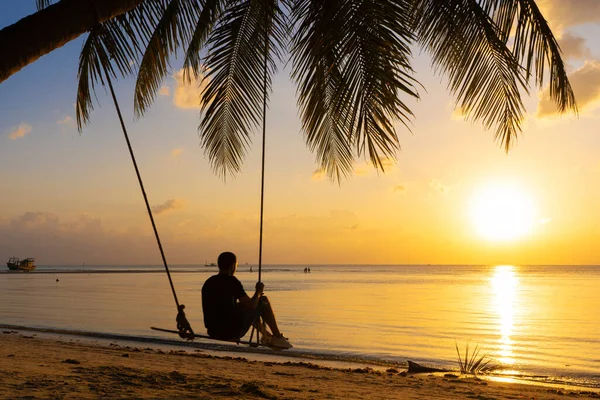 Der Mann Genießt Den Sonnenuntergang Auf Einer Schaukel Tropischen Strand — Stockfoto