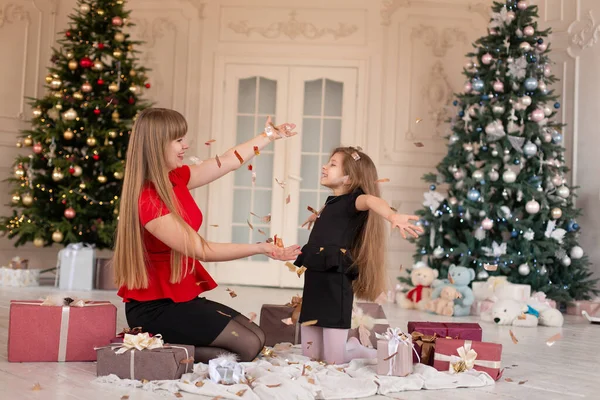 Maa 'lı küçük kız konfeti fırlatıp hediyeleri açıyor. Noel büyüsü. Mutlu bir çocukluğun neşeli anları.