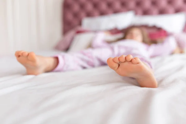 Feet of a girl sleeping in a comfortable bed. Focus on the foot.