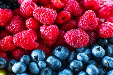 Ahududu ve siyah yaban mersininin yakın çekimi çerçeveyi ikiye böldü. Yaz vitaminleri.