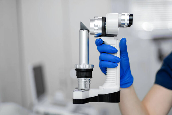 The veterinary ophthalmologist holds professional equipment in his hand - a manual slit lamp
