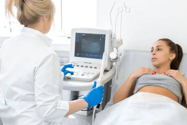 Bir jinekolog, kanepede yatan bir hastaya teşhis koymak için ultrason makinesi kuruyor. Pelvisin iç organlarının transvajinal ultrason tarayıcısı. Kadın sağlığı kavramı.