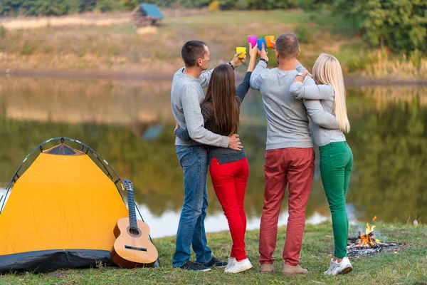 Picnic with friends in at lake near camping tent. Company friends having hike picnic nature background. Hikers relaxing during drink time. Summer picnic. Fun time with friends