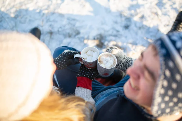 사랑하는 남녀는 마시멜로와 뜨거운 음료를 마시며 겨울에 따뜻하고 융단에 자연을 — 스톡 사진
