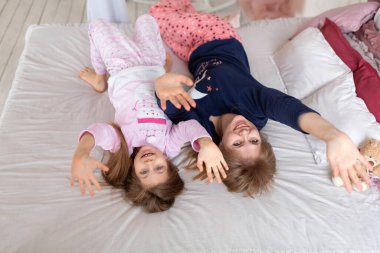 Küçük kız yatakta yatarken annesiyle vakit geçiriyor..