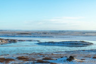 İzlanda ovasında nehir. Bankalar karla kaplı. Kış manzarası, açık alanlar.