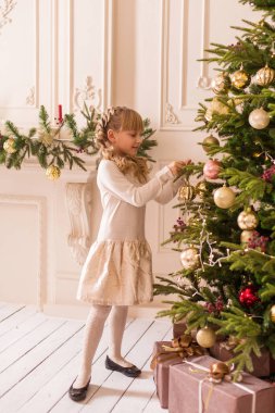 Küçük kız Noel ağacını süslemek için zaman harcıyor. Tatil için hazırlanıyorum. Noel Baba sevinecek..