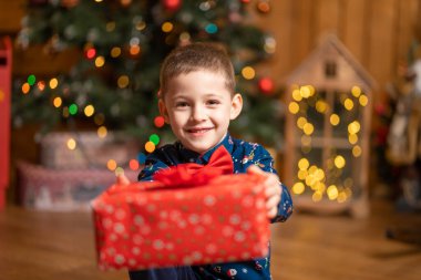 Noel şahanesi, küçük çocuk elinde Noel Baba 'nın hediyesiyle büyük kırmızı bir kutu tutuyor..