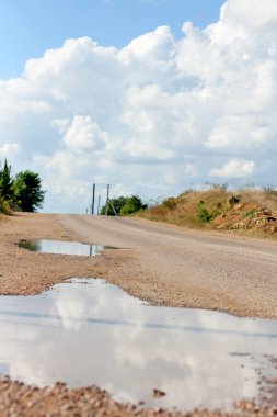 Yağmurdan sonra yoldaki çukurlarda su birikintileri var. Açık hava.