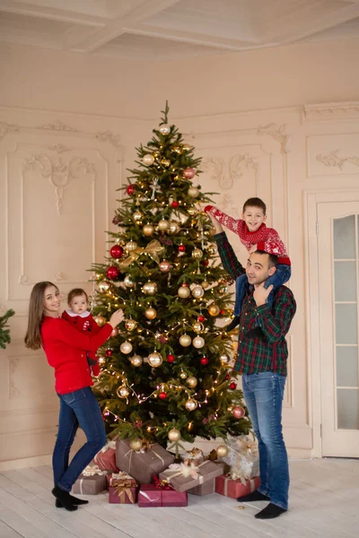 Happy family decorate the Christmas tree indoors together. Loving family. Merry Christmas and Happy Holidays.