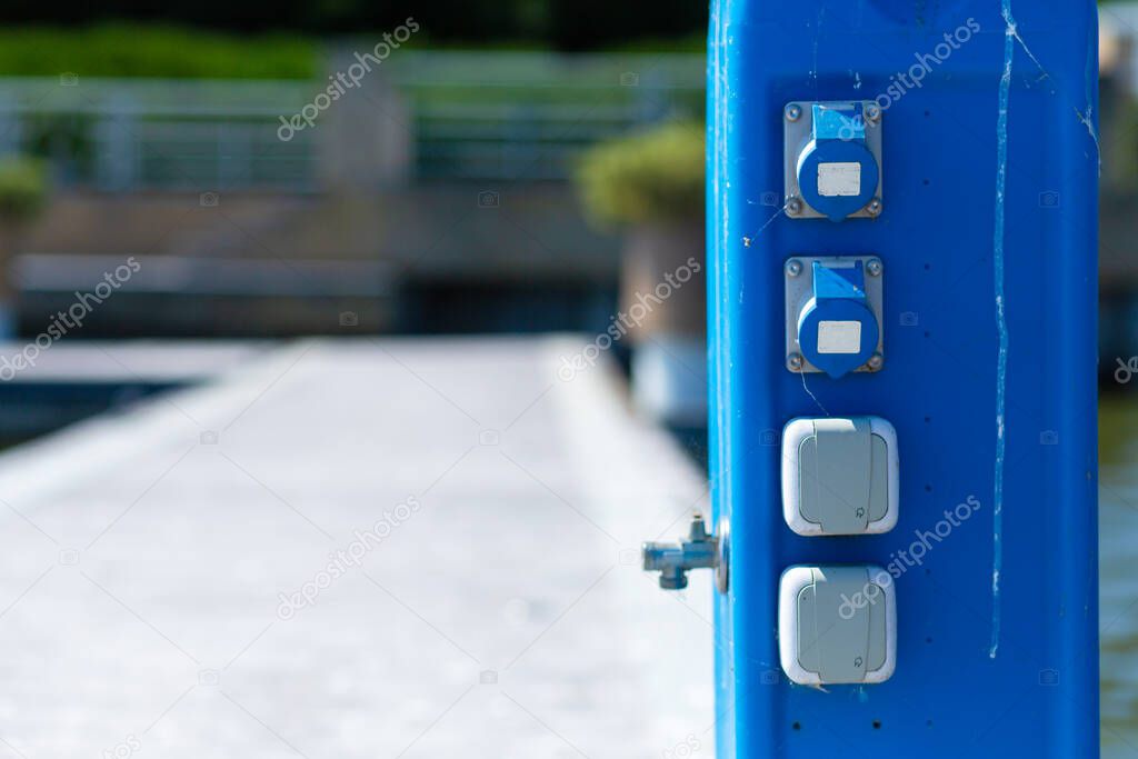 Service pole with electricity sockets and tap with drinking water at the yacht dock.