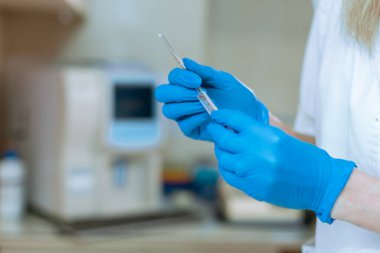 Kapalı kapaklı şeffaf şırınga tutan kauçuk mavi eldivenli doktorun eli.
