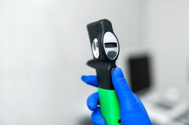 Doktor eli mavi lastik eldiven içinde profesyonel göz doktoru tonometre tutun.