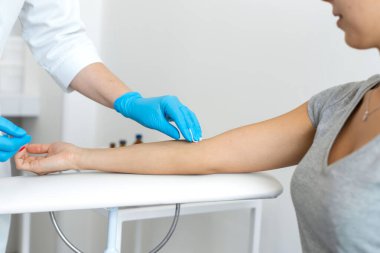 Bir hemşire hastasının elini antiseptiğe batırılmış pamukla siler. Kan örnekleme işlemi.