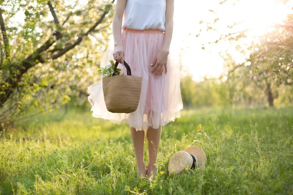 夕日の緑の花の庭を歩いて巻き毛の魅力的な若い女性 春のロマンチックな気分 — ストック写真