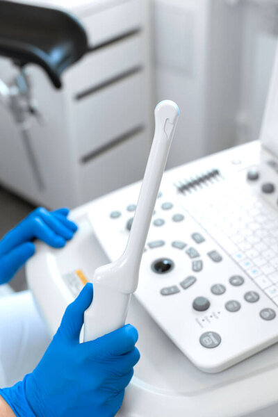 A gynecologist sets up an ultrasound machine. A transvaginal ultrasound scanner of the internal organs of the pelvis. Female health concept.
