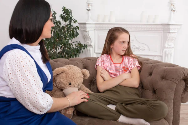 stock image A woman is a professional child psychologist talking with a teenage girl in her cozy office. Psychological assistance to children. Girl teenager offended looks away.