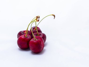 Taze taze sulu kırmızı kirazlar, beyaz arka planda birkaç dut..