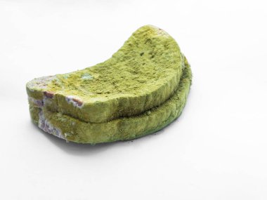 Beyaz arka planda yeşil küfle kaplı bir parça ekmek izole edilmiş..