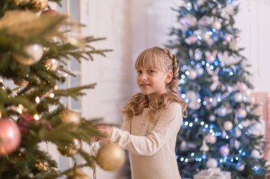 Küçük kız Noel ağacını süslemek için zaman harcıyor. Tatil için hazırlanıyorum. Noel Baba sevinecek..