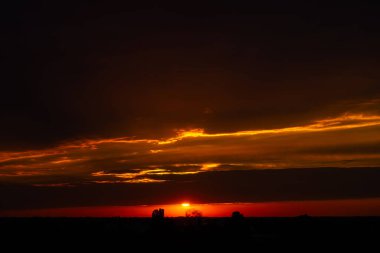 Gün batımında bulutlu bir gökyüzü. Siyah bulutlar arasındaki turuncu ışık çizgisi. Güzel bir doğa manzarası..