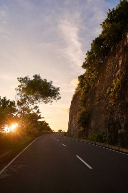 Kayalık gün batımında okyanusa giden yol boyunca sarkıyor.