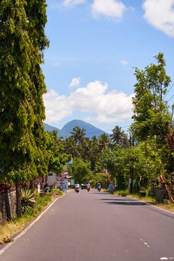 Bir motosikletli Asya 'da manzaralı asfalt bir yolda gidiyor.