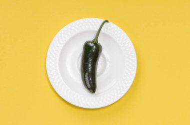 Sarı arka plan üzerinde plaka üzerinde tek yeşil jalapeno biber