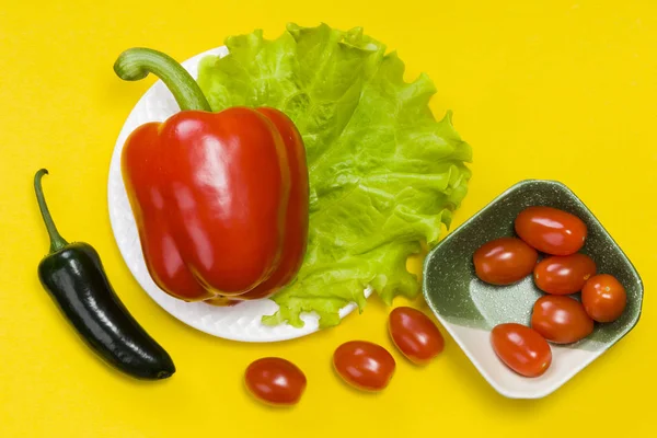 Stillleben von Jalapeño-Paprika, Paprika, Tomatenkirsche, Salat auf gelbem Hintergrund — Stockfoto