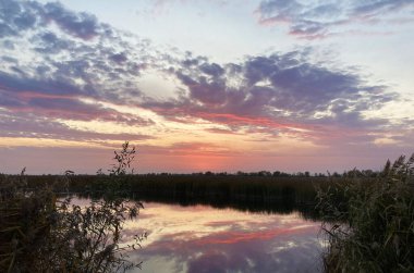 Kıyı nehrinde gün batımının olduğu güzel bulutlar.