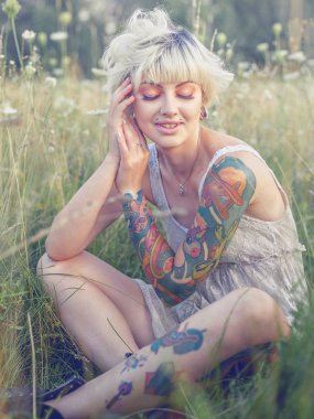 Keskin görünüşlü sarışın çayırda yürüyor..