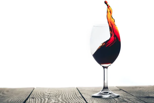 Un vino rosso versato in un bicchiere su fondo bianco — Foto Stock