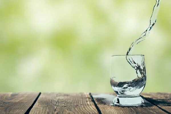 A splash of water in a glass on wood — Stock Photo, Image