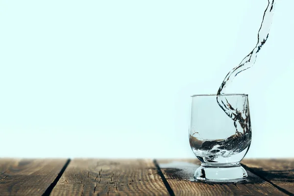 A splash of water in a glass on wood — Stock Photo, Image