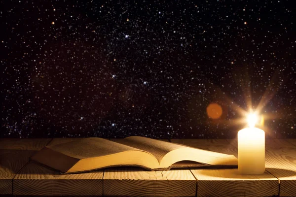 Uma bíblia sobre a mesa à luz de uma vela — Fotografia de Stock