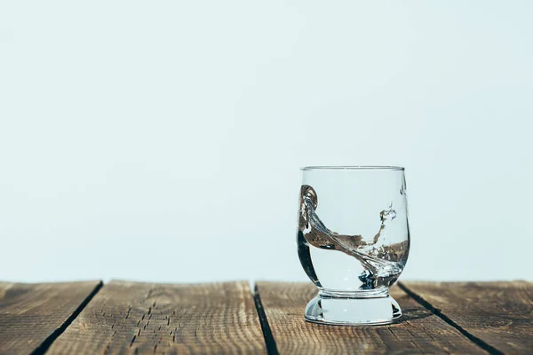 A splash of water in a glass on wood — Stock Photo, Image