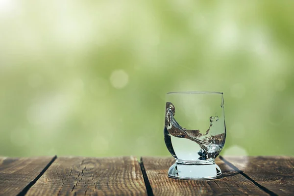 A splash of water in a glass on wood — Stock Photo, Image