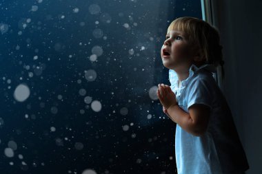 çocuk pencereden Noel gününde görünüyor.
