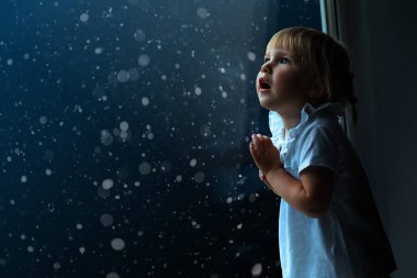 çocuk pencereden Noel gününde görünüyor.
