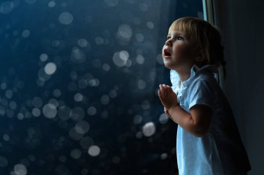 çocuk pencereden Noel gününde görünüyor.