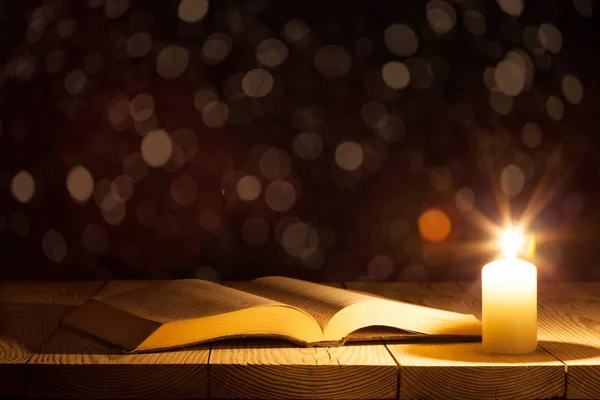 Uma bíblia sobre a mesa à luz de uma vela — Fotografia de Stock