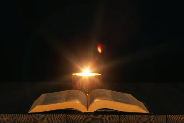 Библия на столе в свете свечи — стоковое фото