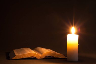 a bible on the table in the light of a candle clipart